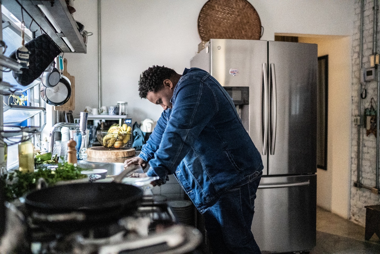 Tired-looking man at home in his kitchen.