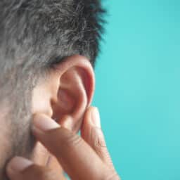 Man holds hand to ear