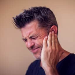 Man experiencing tinnitus holds his ear