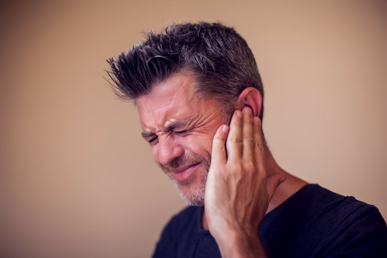 Man experiencing tinnitus holds his ear