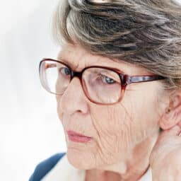 Elderly woman with arthritis straining to hear