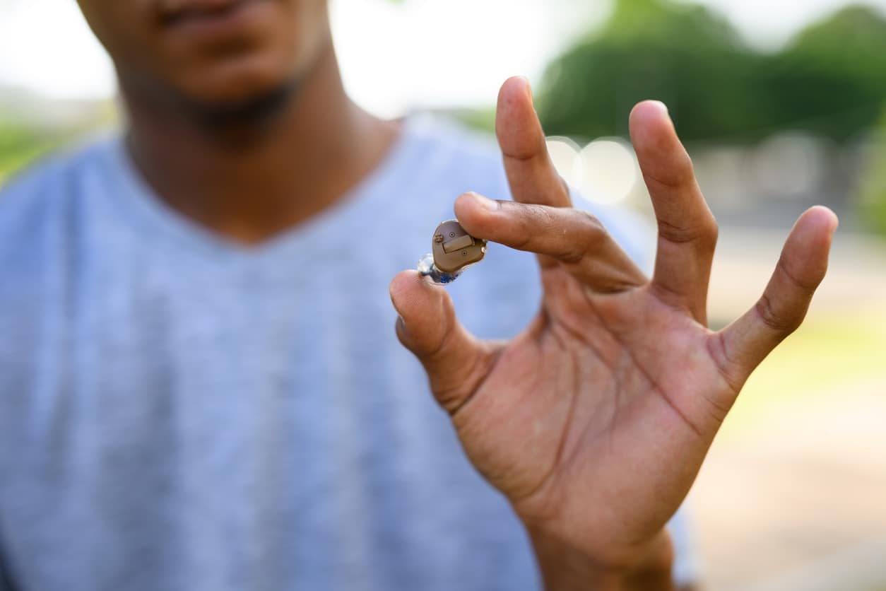 Close up of a person's hand holding his new hearing aid.