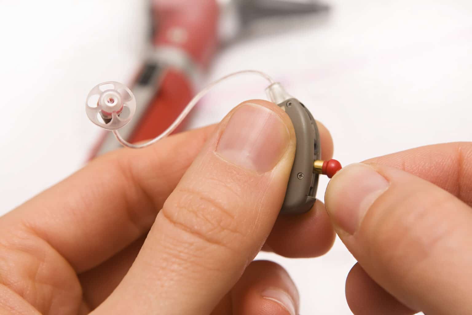 Audiologist performing routine maintenance on a hearing aid to extend its lifespan