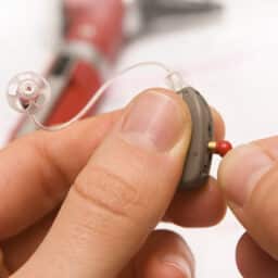 Audiologist performing routine maintenance on a hearing aid to extend its lifespan