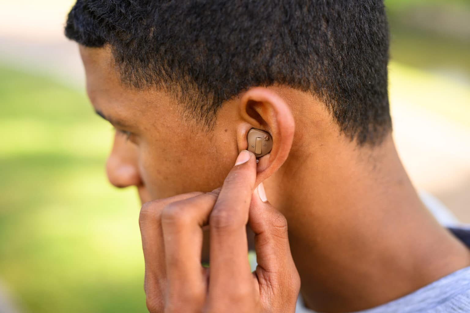 Man reaching up to his ear to adjust his hearing aid.