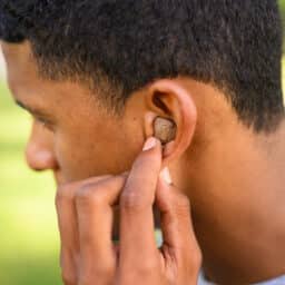 Man reaching up to his ear to adjust his hearing aid.