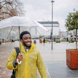 Happy man out for a walk holding an umbrella in the rain.