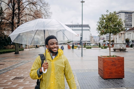 Happy man out for a walk holding an umbrella in the rain.