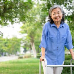 Smiling woman with a walker going for a stroll in a local park.