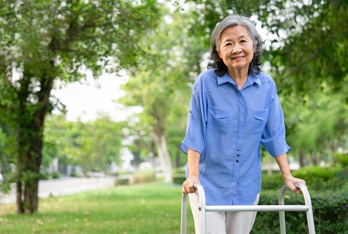 Smiling woman with a walker going for a stroll in a local park.