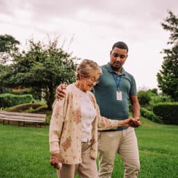 Balance specialist working with a patient walking outdoors to strengthen balance.