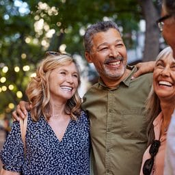 Older men and laughing women chatting together during a walk. Close up face of cheerful retirees enjoying time in a lively city street.